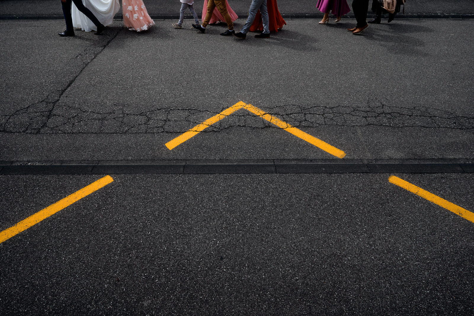 Photo créative documentaire d'un cortège de mariage à pied, utilisant un arrêt de bus dans le cadrage ne montrant que les pieds