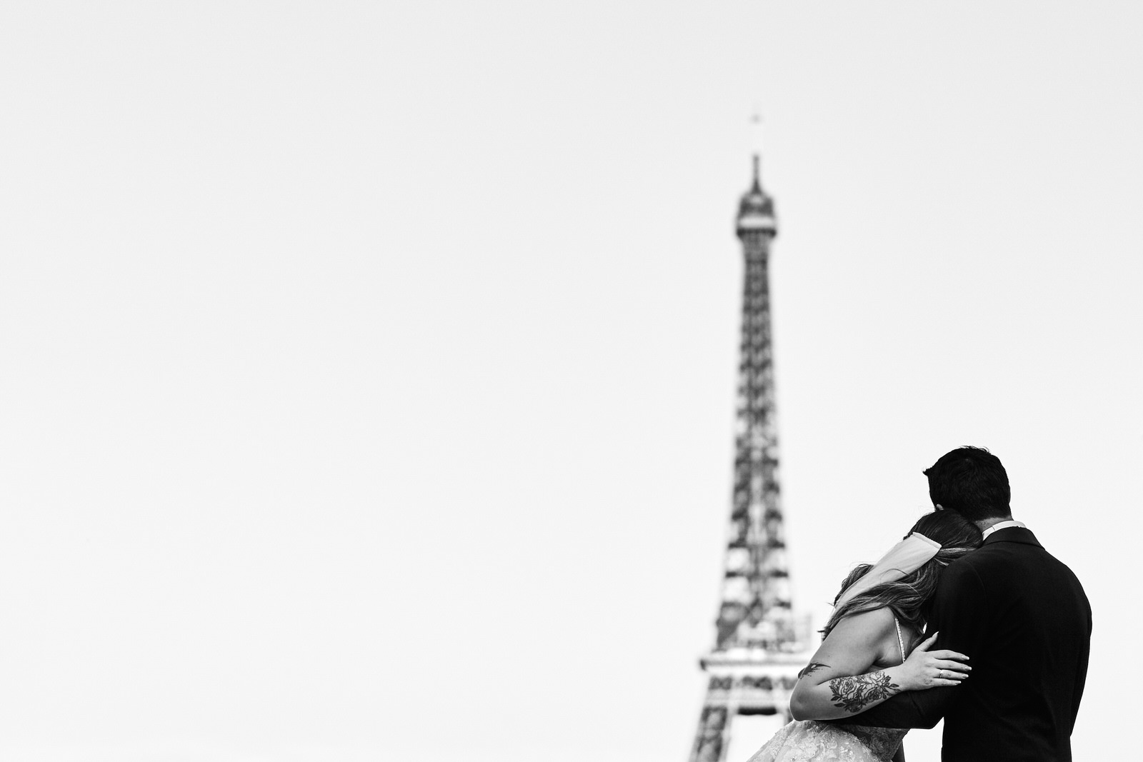 Couple de mariés enlacés regardant la tour Eiffel, photo graphique et minimaliste