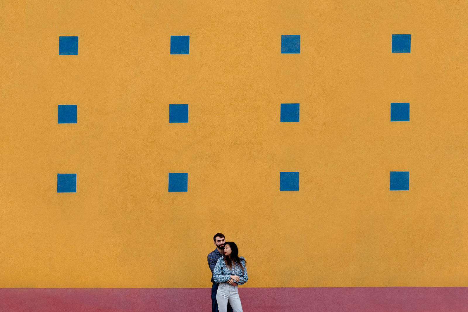 Couple d'amoureux devant un mur jaune, rouge et bleu