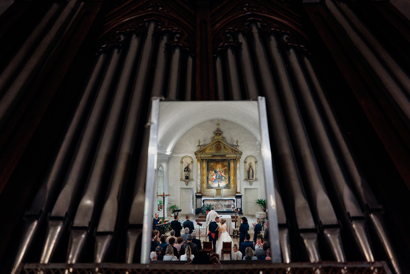 les mariés s'embrassent dans l'église la photo est prise dans le reflet d'un miroir de l'orgue