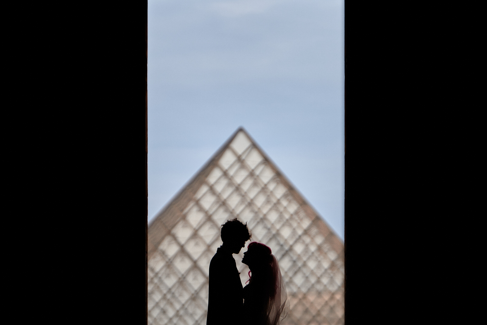 couple en silhouette devant la pyramide du Louvre