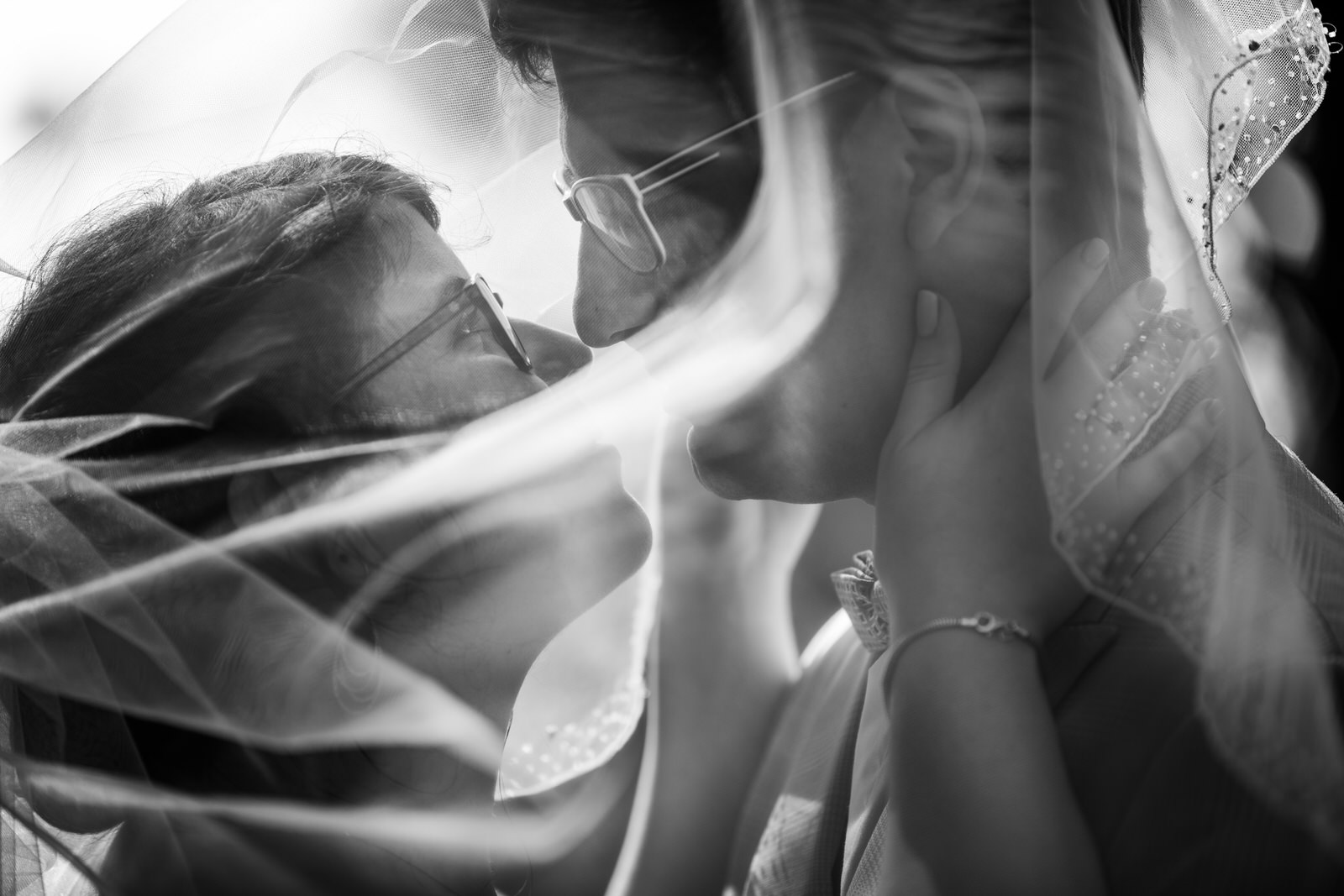 couple s'embrassant sous le voile de la mariée