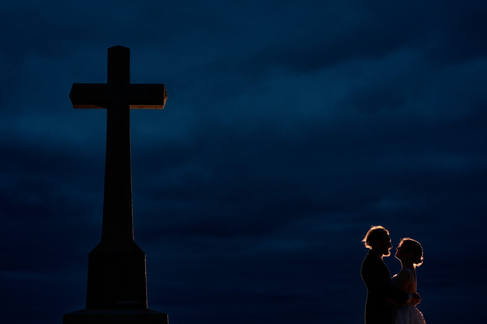 couple face à face à l'heure bleu à côté d'une croix