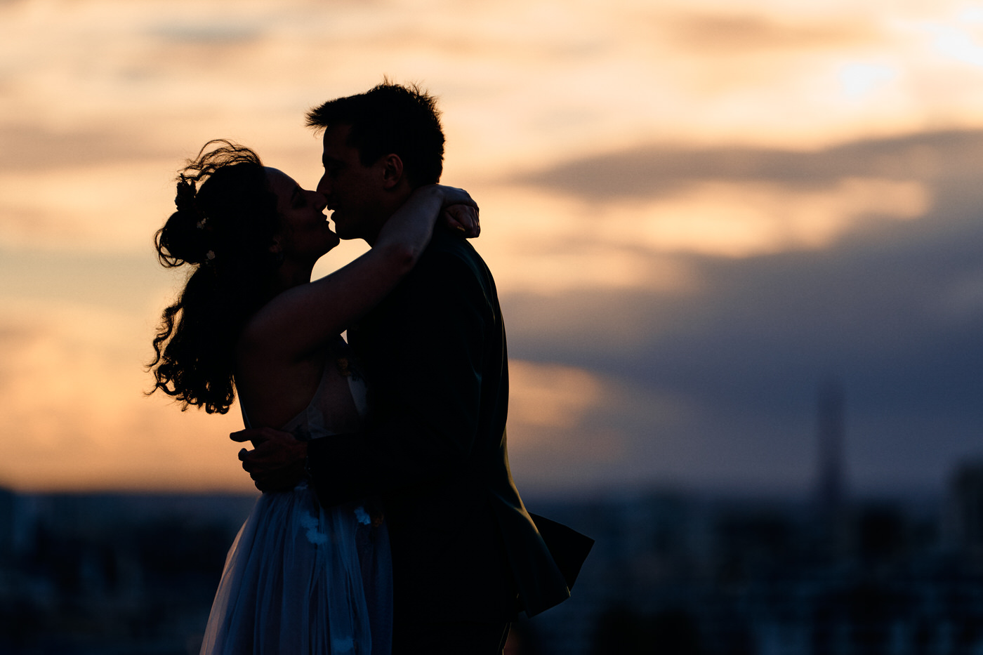 couple face à face en silhouette au coucher de soleil sur le toit de la philharmonie de paris