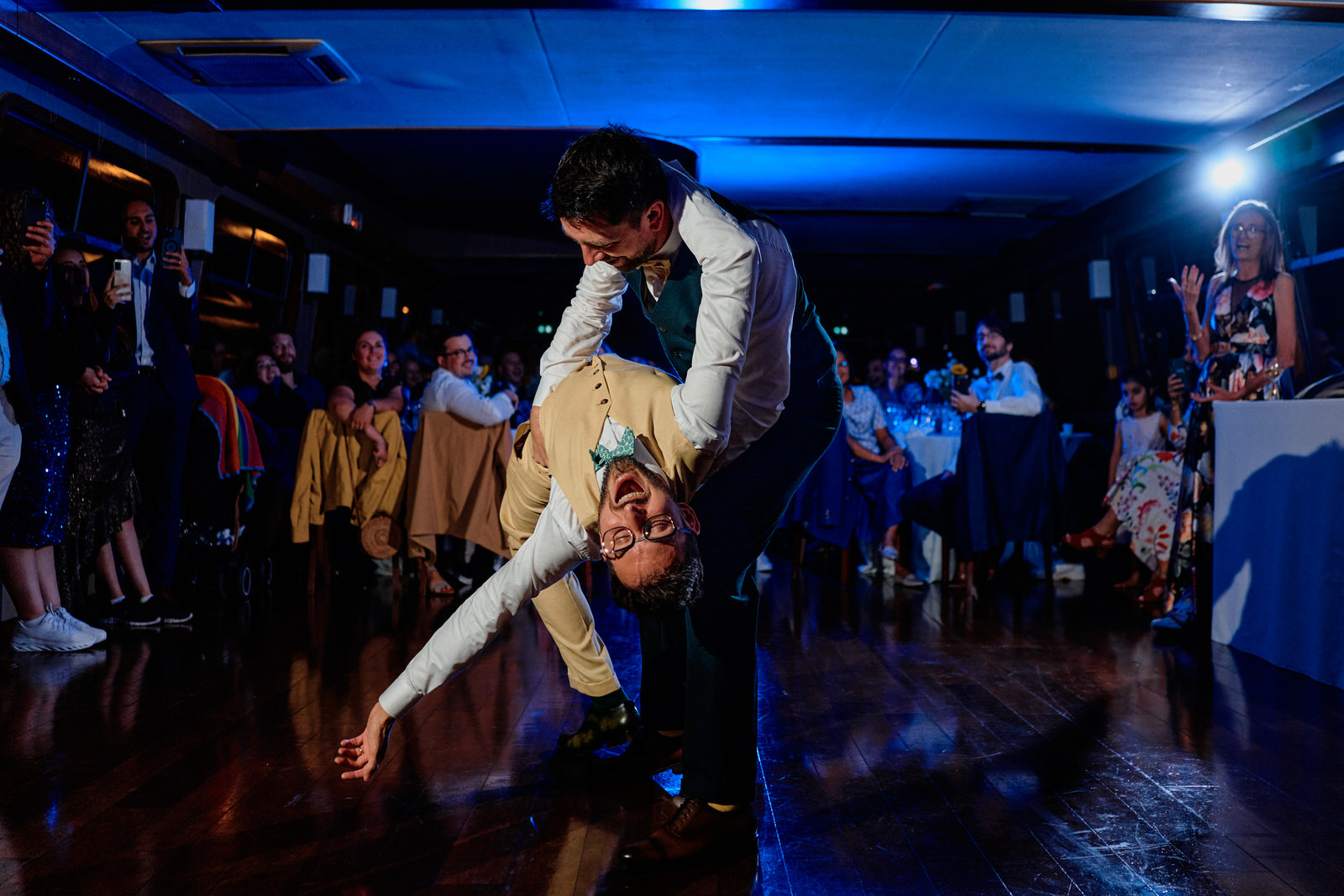 les mariés font leur première danse sur le dancefloor d'une peniche parisienne. Le marié fait pencher en arrière le marié
