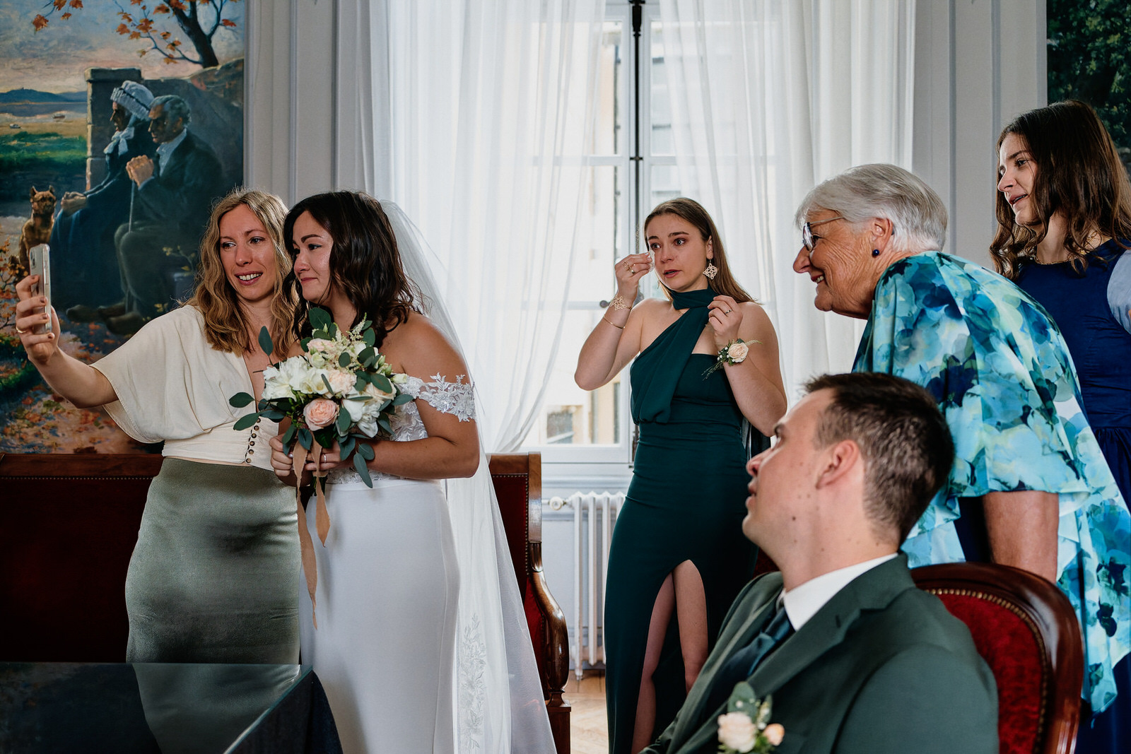 Scène de vie capturée à la fin de la cérémonie civile. La mariée est en appel visio avec sa famille pendant que les invités présents se remettent de leurs émotions