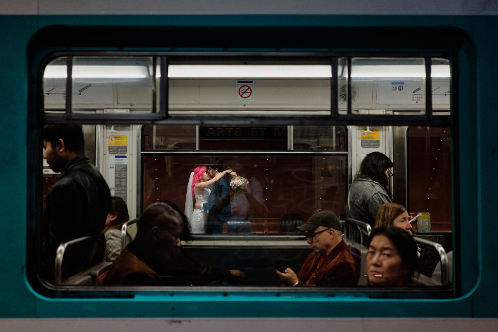 photo d'un couple s'embrassant dans une station de métro de Paris, au premier plan le métro et des parisiens blasés