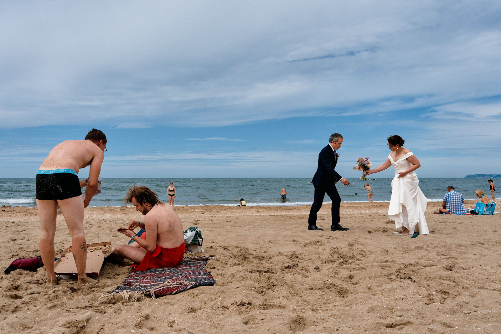 photo d'un couple de mariés sur une plage, au milieu des touristes