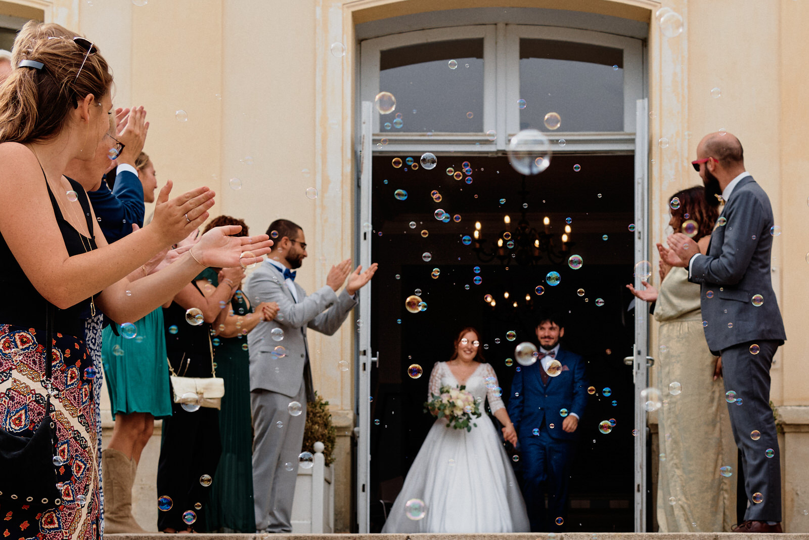 Sortie de mairie sous les bulles, photo prise par un photographe de mariage, les bulles tombent pile sur les yeux de la mariée